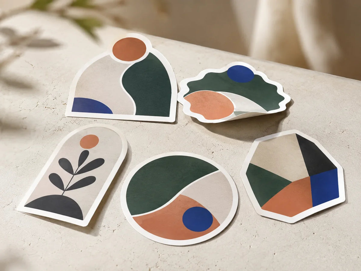 Custom die-cut vinyl stickers arranged on a warm neutral background